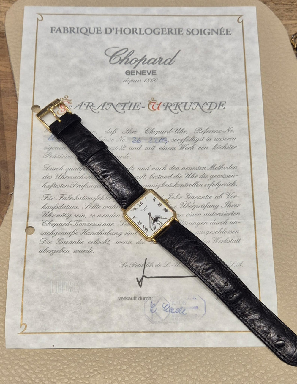 damenuhr-chopard-gebraucht-schraeg-liegend-auf-zertifikat-mondphase-lederband-weißes-Zifferblatt