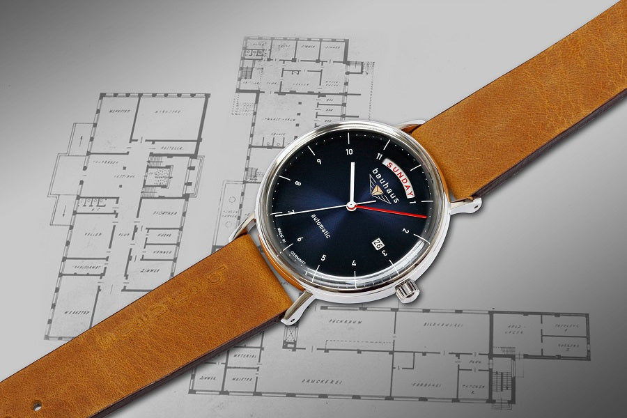 bauhaus Uhr liegt schraeg auf Architektenplan